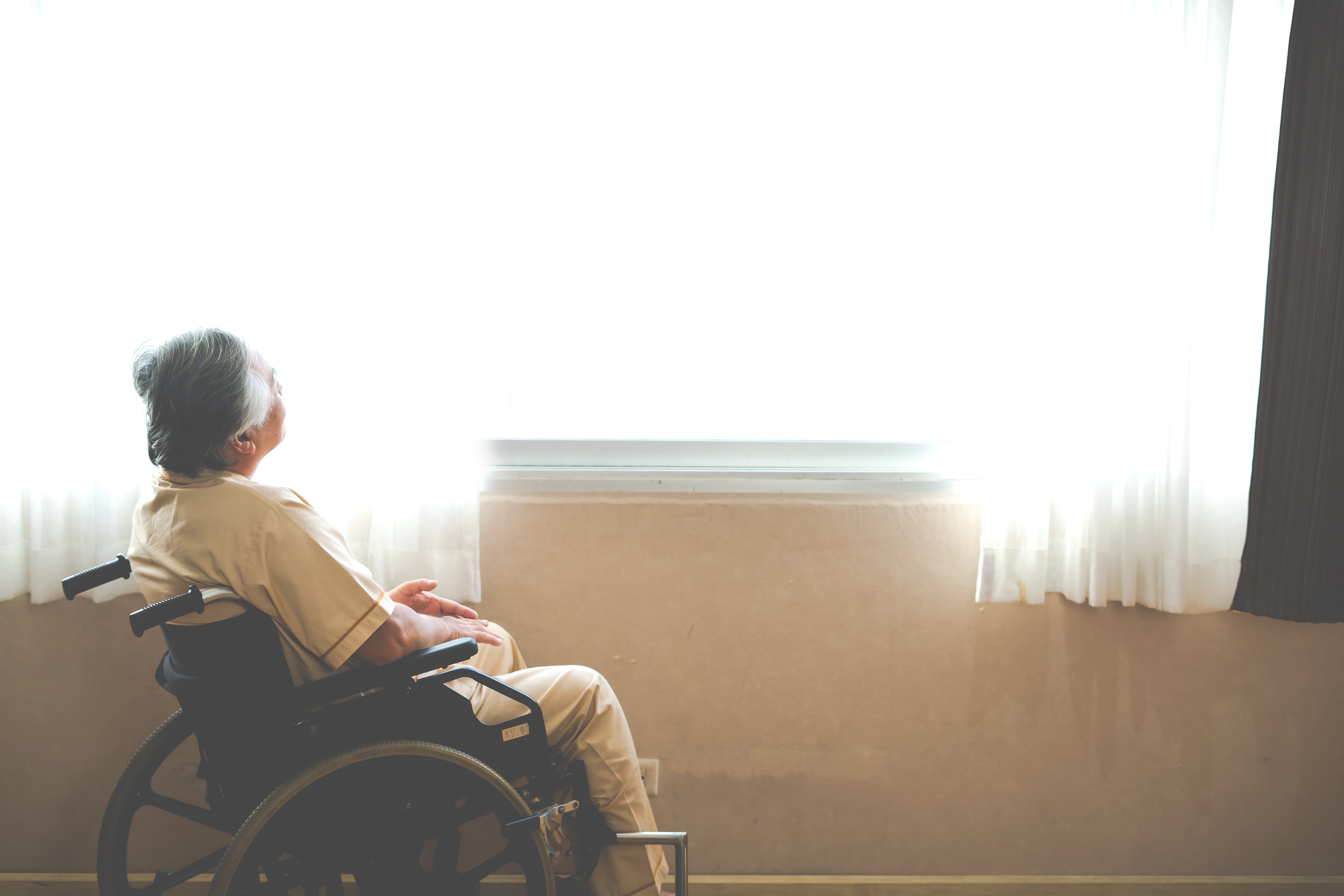 Woman sitting in a wheelchair next to a window