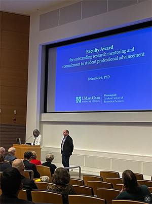 a picture of Dr. Brian Kelch standing at the front of a lecture hall to receive an award