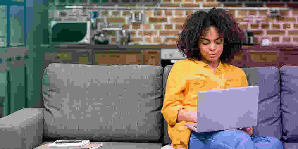 Young Black woman on couch with laptop