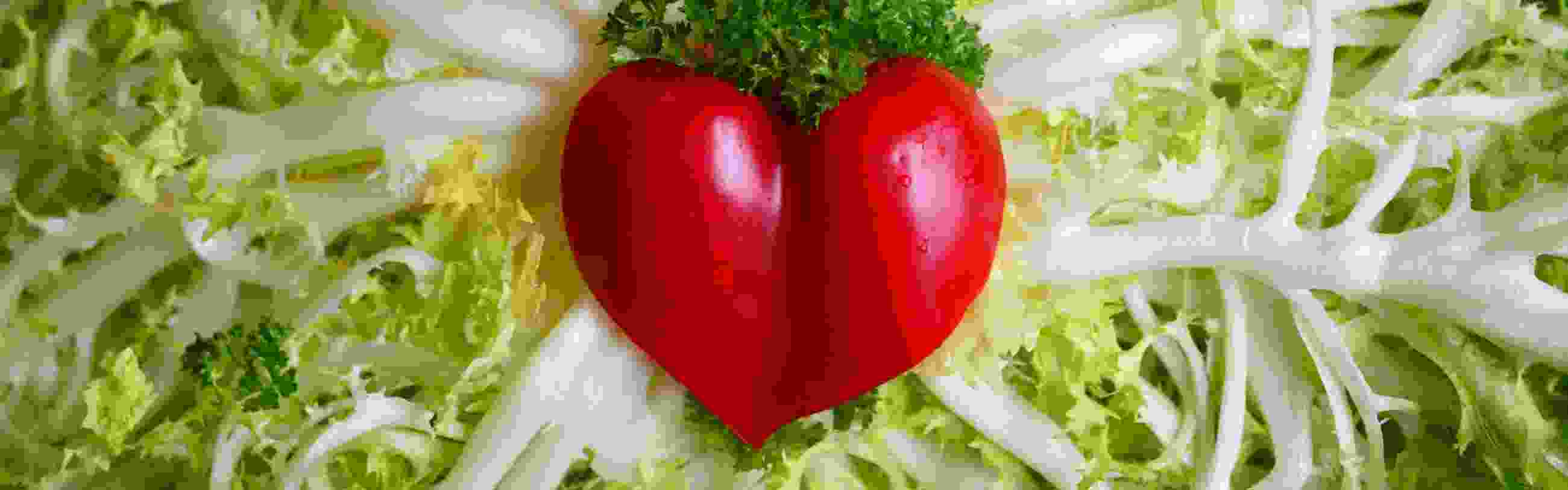 A heart-shaped pepper laying in the center of a bed of artery-like lettuce leaves