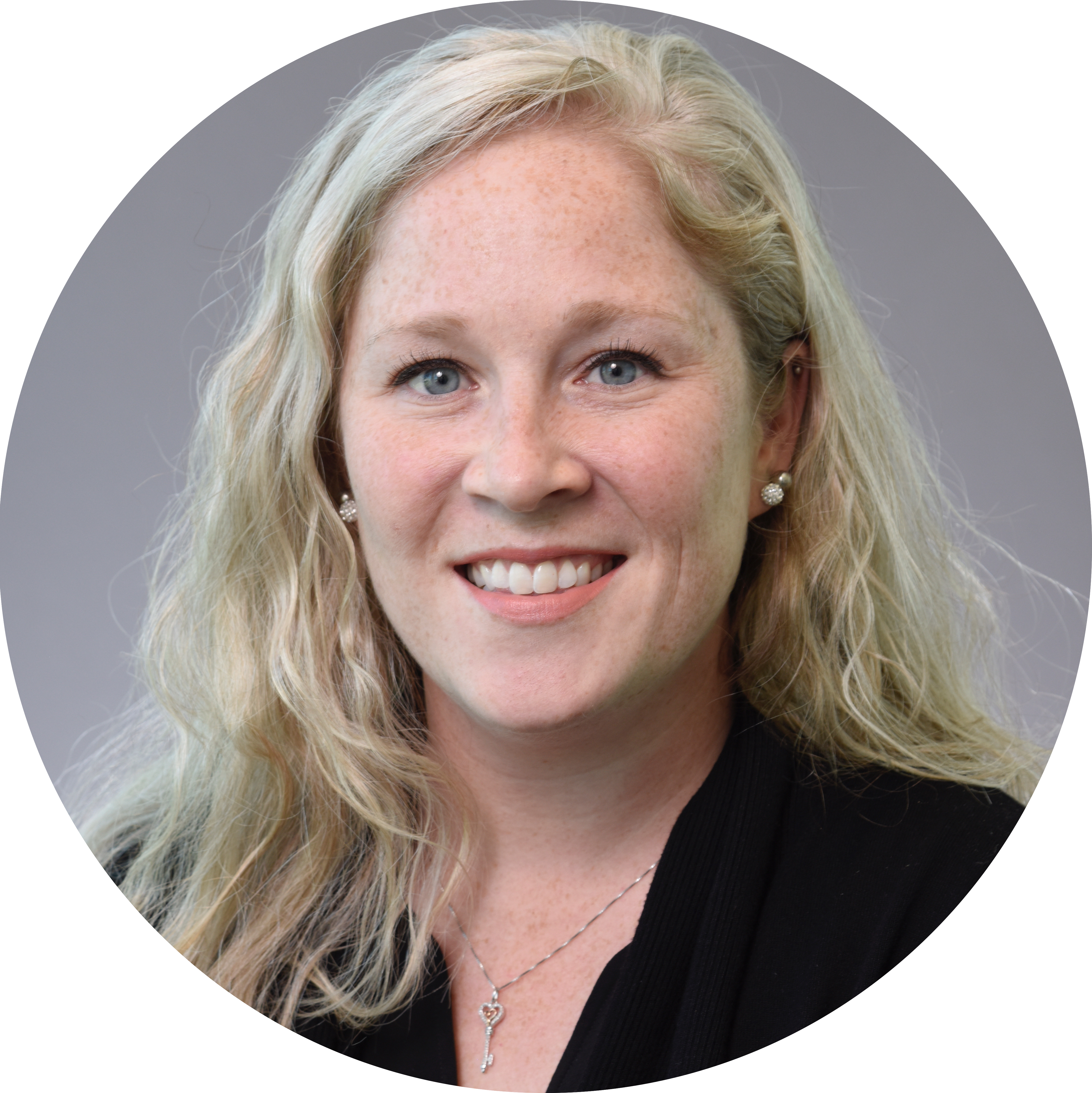 Circular portrait of Dr. Justine Pinskey. She has long blonde hair and is wearing a black blazer and necklace and smiling.