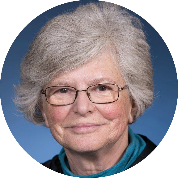 Circular portrait of Dr. Catarina Kiefe, who has short white hair and glasses and is wearing a teal turtleneck and smiling