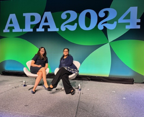 two woman in business attire sitting on a stage