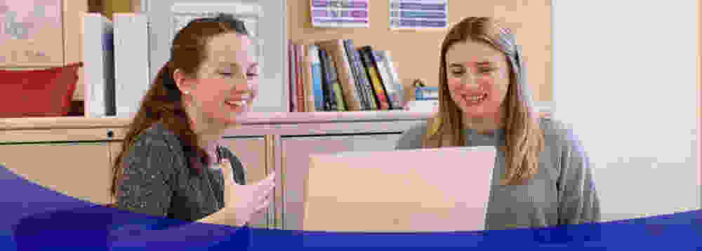 two woman smiling chatting in an office setting