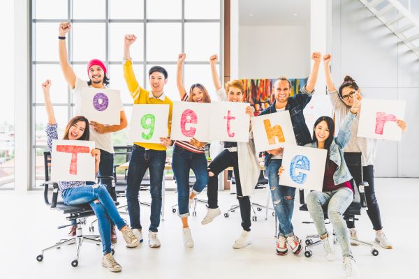 group of diverse teens in colorful clothes each holding a letter that spells together