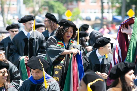 Asia Matthew-Onabanjo, MD, PhD, and classmates prepare to don degree hoods.