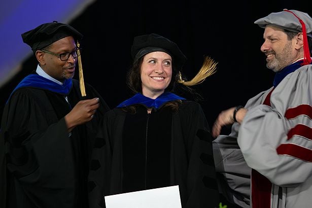 Molly Jurewicz of the GSBS receives her hood from Brian Lewis and her mentor, Lawrence Stern.